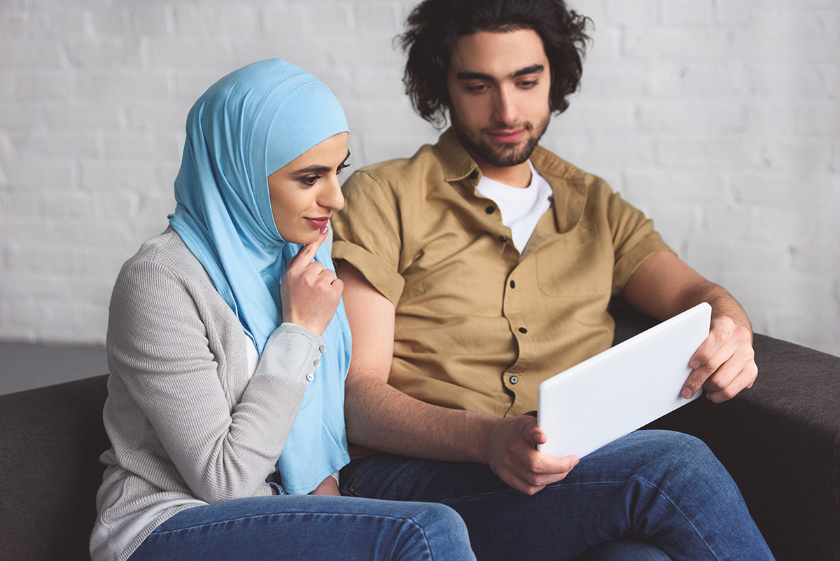 muslim couple using tablet in living room